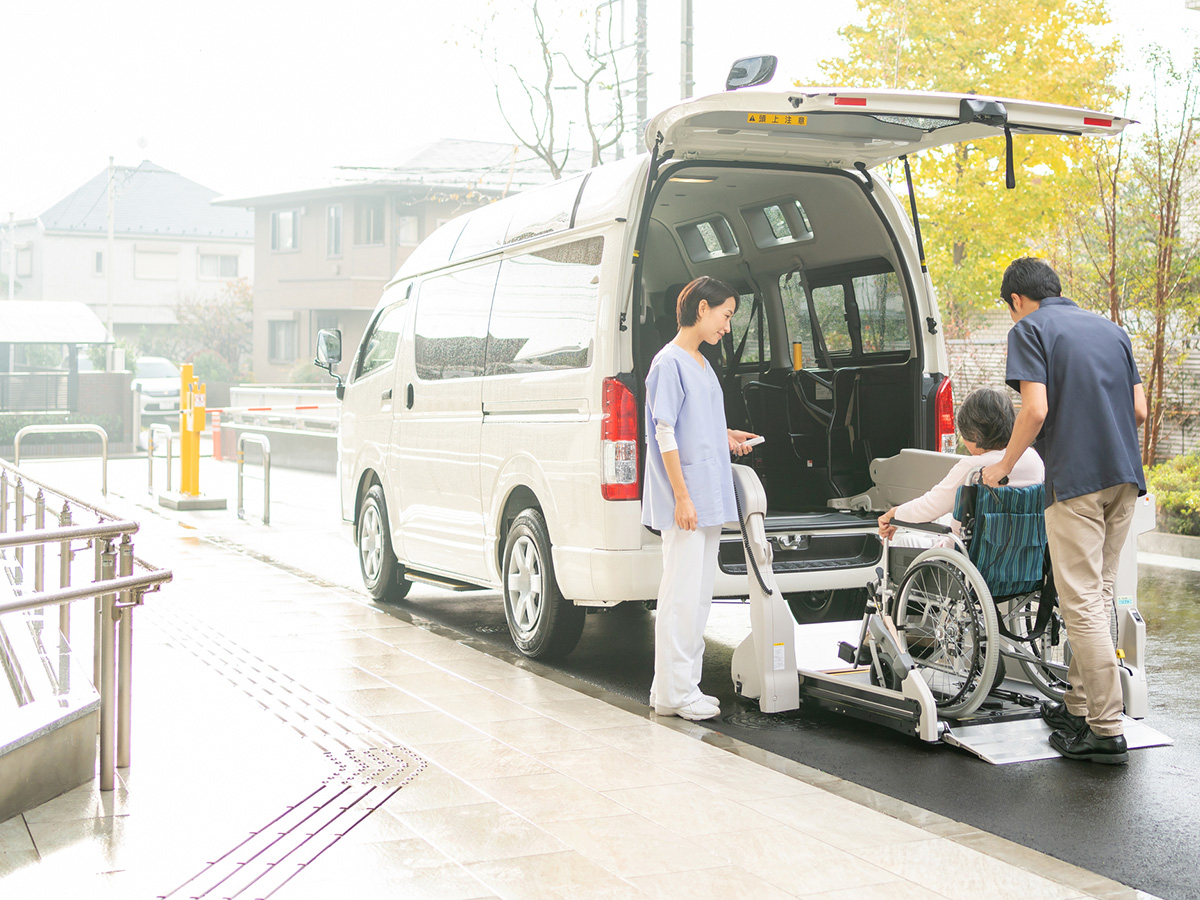 介護施設の送迎車に車椅子利用者を乗降させるスタッフ